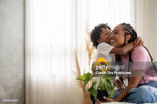 son handing flower to his mother on mother's day - composietenfamilie stockfoto's en -beelden