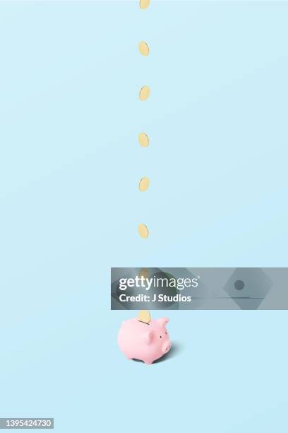 gold coins falling into pink piggy bank - solid gold fotografías e imágenes de stock