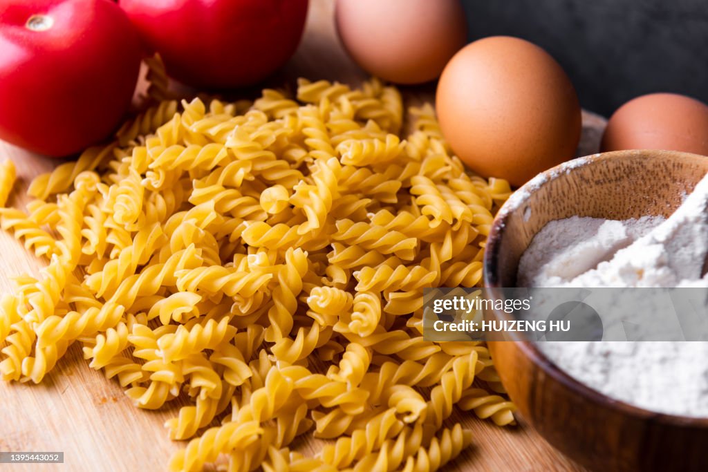 Fusilli pasta on wooden table tomatoes eggs