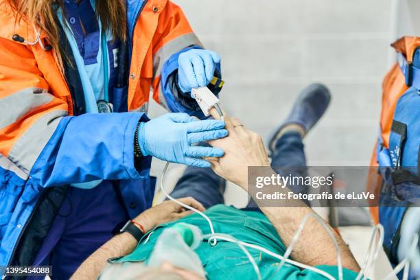 woman paramedic inside ambulance with a patient reading heartbeat with an oximeter where the patient is on stretcher. - stretcher stock-fotos und bilder