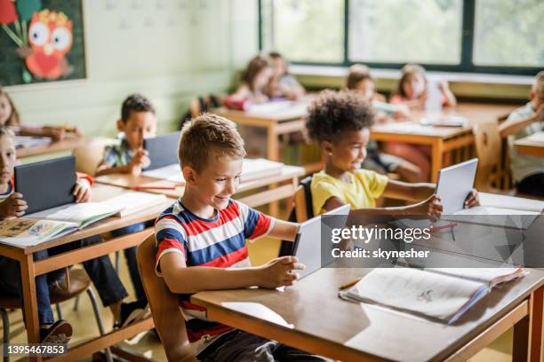 smiling schoolboy e-learning over digital tablet in the classroom. - school tablet stockfoto's en -beelden