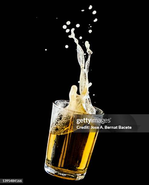 impact of a glass with beer falling to the ground on a black background. - bier stockfoto's en -beelden