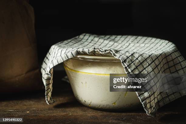 focaccia bread dough rising in a glass bowl covered with a cloth - gluren stock pictures, royalty-free photos & images