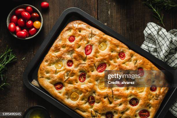 draufsicht auf frisch gebackenes focaccia-brot mit zutaten - focacciabrot stock-fotos und bilder