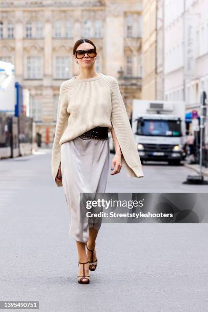 Federrock founder Anna von Schilcher wearing a beige colored cashmere pullover by Max Mara, a light silver satin dress by Max mara, a dark brown wide...