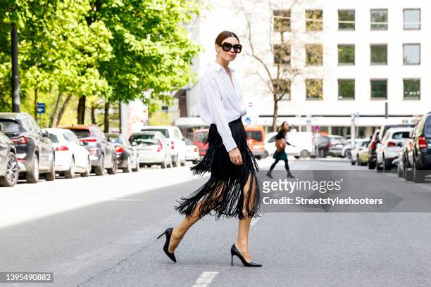 Federrock founder Anna von Schilcher wearing a white blouse by Seidensticker x Glamometer, a black fringe dress by The Outnet, black pumps by Manoli...