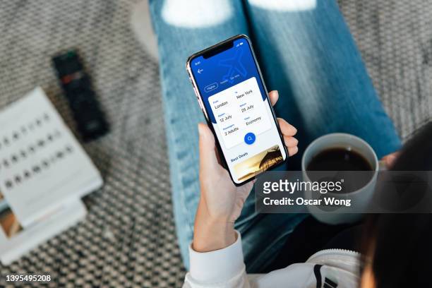 woman using smartphone to book flight tickets and plan holiday - femme de dos smartphone photos et images de collection