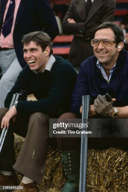 British Royal Prince Andrew and Greek Royal Constantine II of Greece, their shotguns broken over the crook of their right arms, attend a clay pigeon...