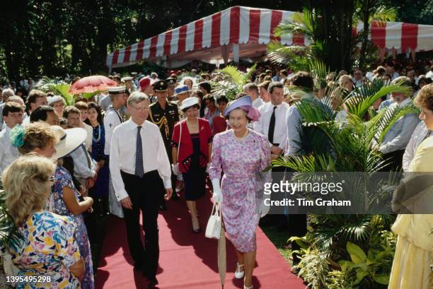 Queen Elizabeth II, wearing a pink, white and purple floral pattern outfit with a Frederick Fox hat, and guests attend a garden party at Eden Hall,...