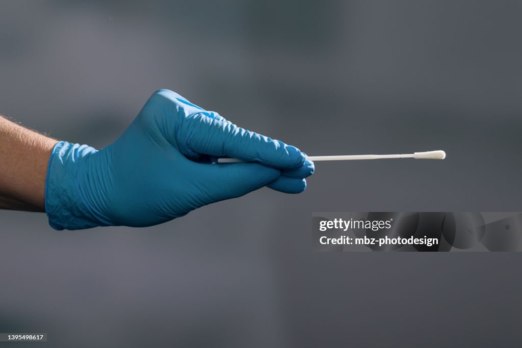 Close up of a hand handling a smear test or swab test in a medical laboratory