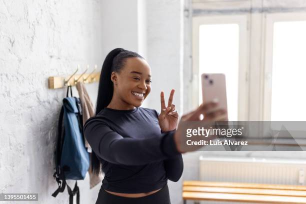young african woman taking selfies in the dressing room  at gym - pferdeschwanz stock-fotos und bilder