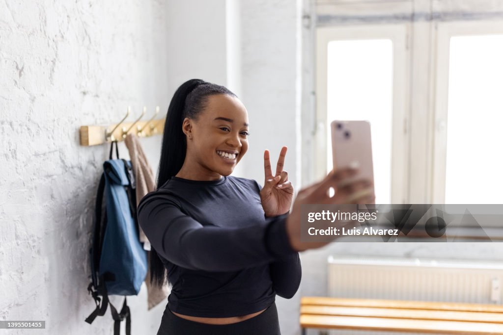 Young African woman taking selfies in the dressing room at gym