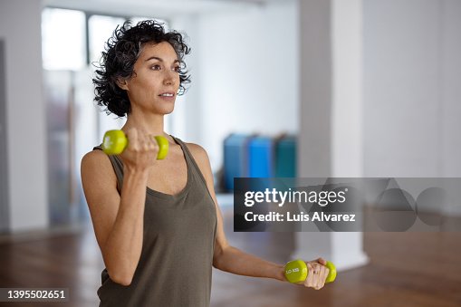Fit mature woman doing dumbbell workout in gym Fit mature woman doing dumbbell workout in gym