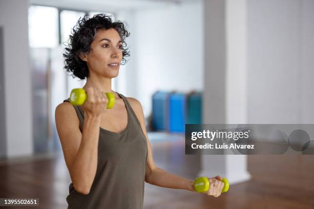 fit mature woman doing dumbbell workout in gym - entraînement sportif photos et images de collection