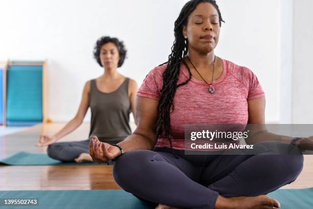 healthy african woman meditating in yoga class - budismo imagens e fotografias de stock