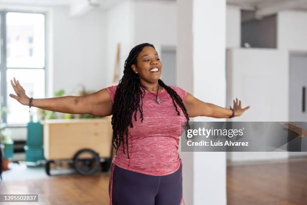 plus size african woman doing stretching workout in yoga studio - woman standing exercise stockfoto's en -beelden