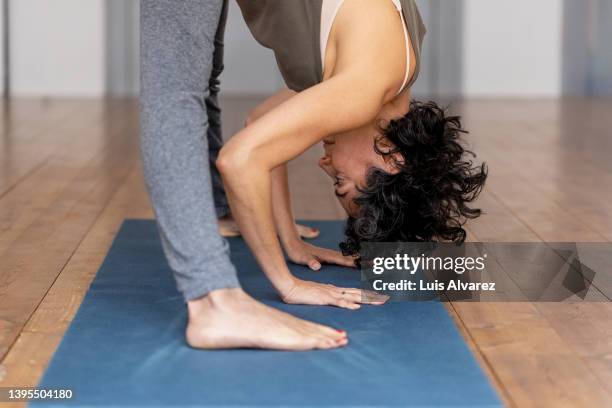 side view of a mature woman practicing yoga in gym - woman bending over imagens e fotografias de stock