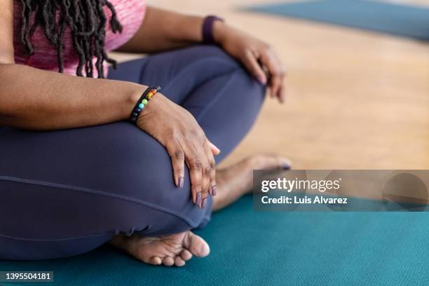 close-up of plus size woman sitting on exercise mat at yoga class - hand on knee fotografías e imágenes de stock