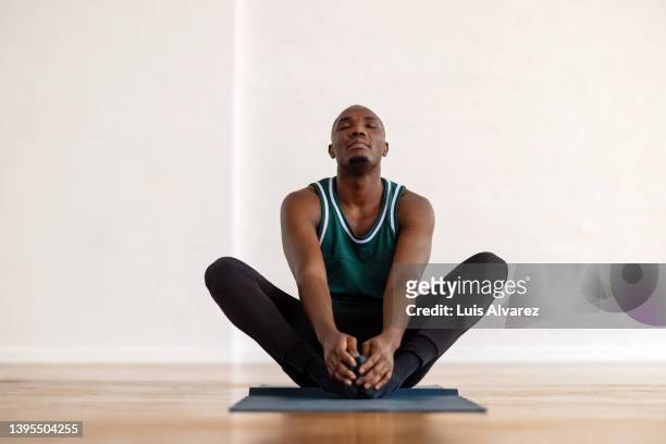 african man practice yoga in the butterfly position in yoga class - dehnen stock-fotos und bilder