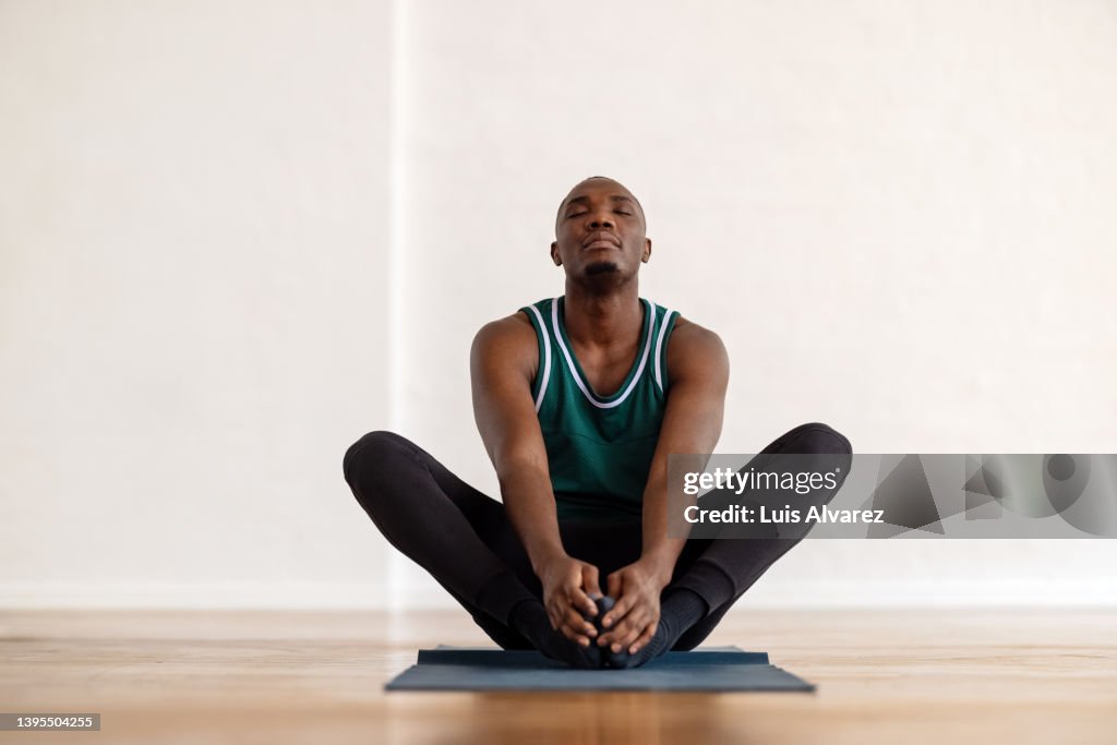African man practice yoga in the butterfly position in yoga class