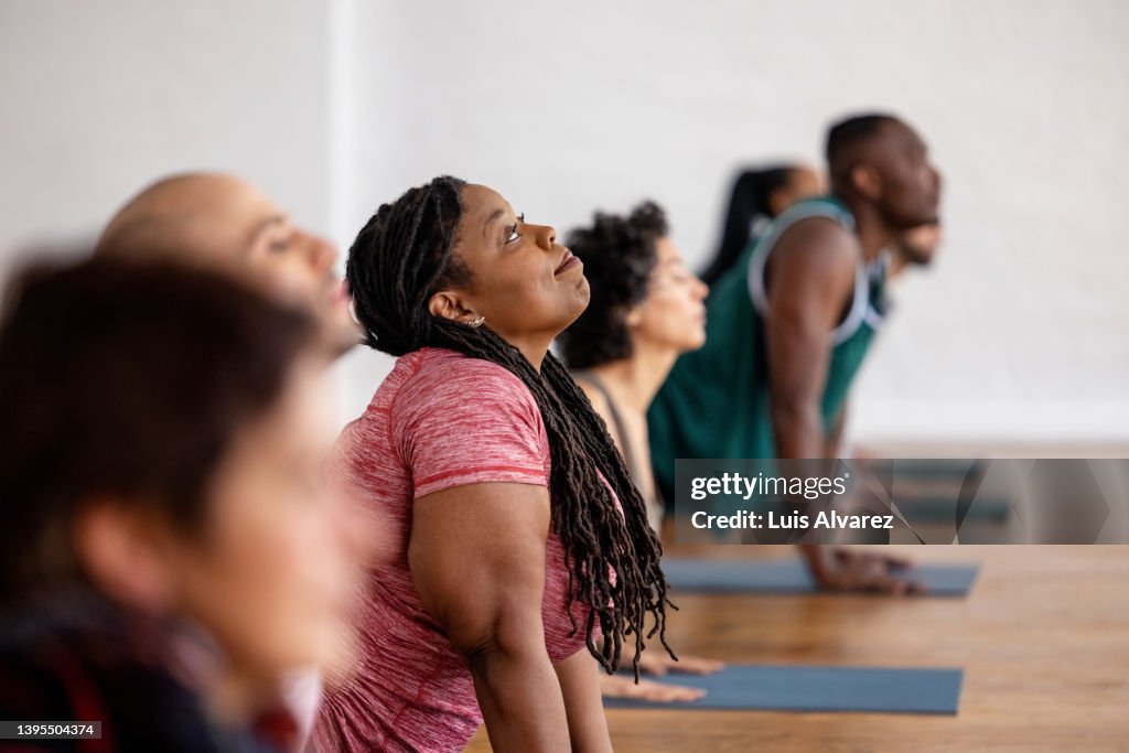 Diverse group of people doing stretching yoga workout in gym