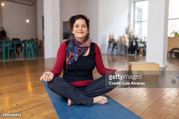 mature woman sitting and meditating in lotus pose - lotussitz stock-fotos und bilder