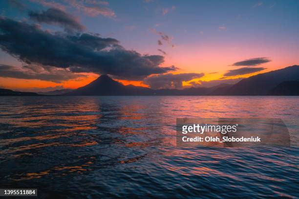 scenic view of atitlan lake in guatemala at sunset - volcán de fuego guatemala stock pictures, royalty-free photos & images
