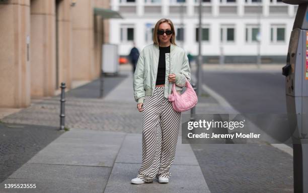 Sonia Lyson seen wearing black Celine Triomphe sunglasses, a black top from Edited, a pale green bomber jacket from Lala Berlin, a black and white...