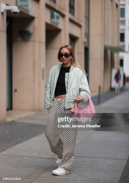 Sonia Lyson seen wearing black Celine Triomphe sunglasses, a black top from Edited, a pale green bomber jacket from Lala Berlin, a black and white...