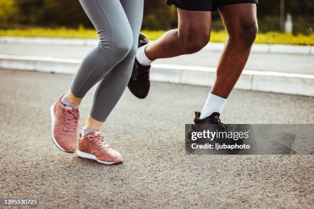 feet of two friends running on the city street - sporting footwear stock pictures, royalty-free photos & images