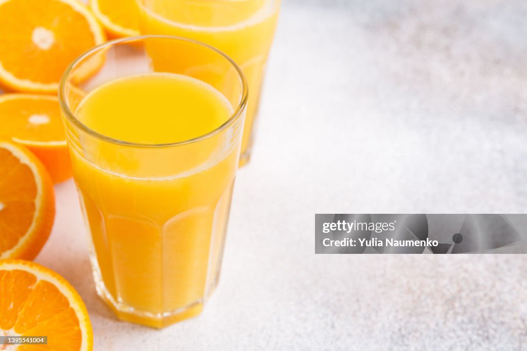 Fresh orange juice and oranges on light background.