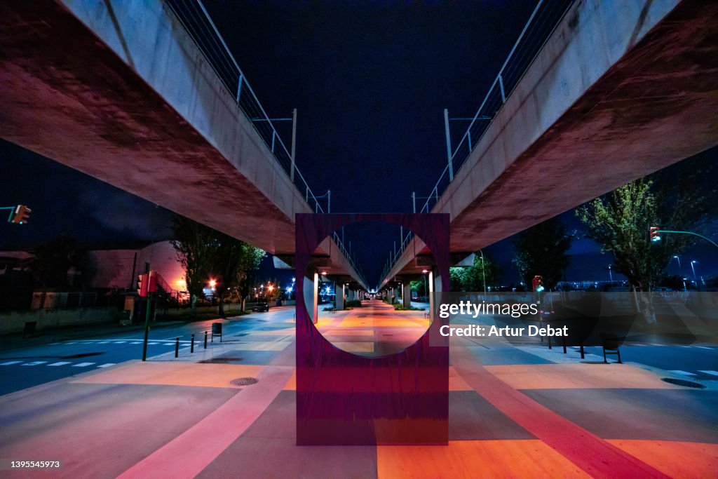 3D digital object with circle installed under stunning elevated train at night.