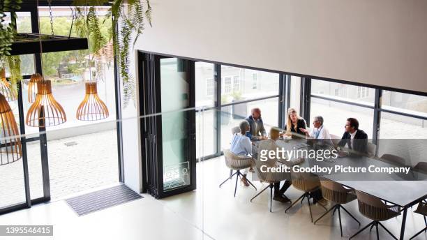 diverse businesspeople talking during a meeting in an office boardroom - office elevated view stock pictures, royalty-free photos & images