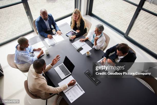 diverse businesspeople sitting around a boardroom table during a meeting - conference table stock pictures, royalty-free photos & images