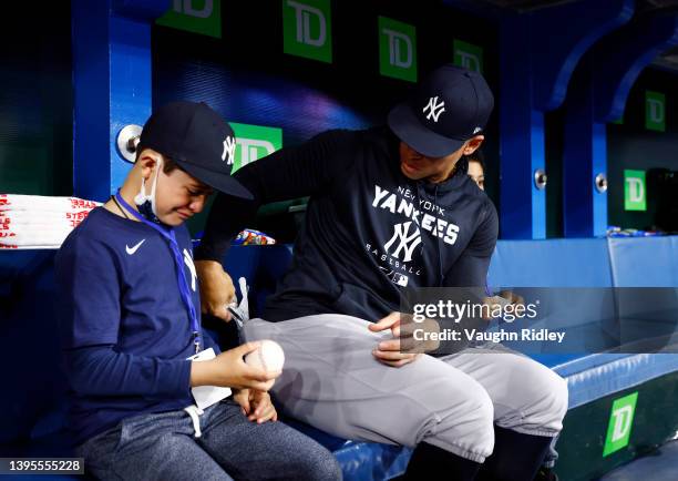 Aaron Judge of the New York Yankees gives the home run ball to fan Derek Rodriguez after signing it prior to a MLB game against the Toronto Blue Jays...