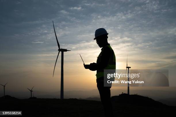 silhouette of a male power engineer standing in a wind farm - construction site and silhouette stock pictures, royalty-free photos & images