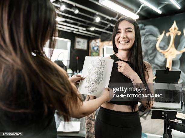 mexikanische tätowiererin schafft kunst auf dem arm des kunden - fotografia da studio stock-fotos und bilder