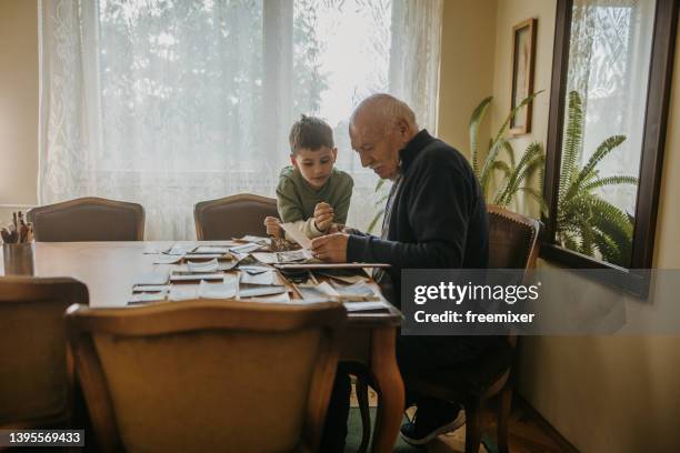 grandfather showing pictures to grandson - nostalgie stockfoto's en -beelden