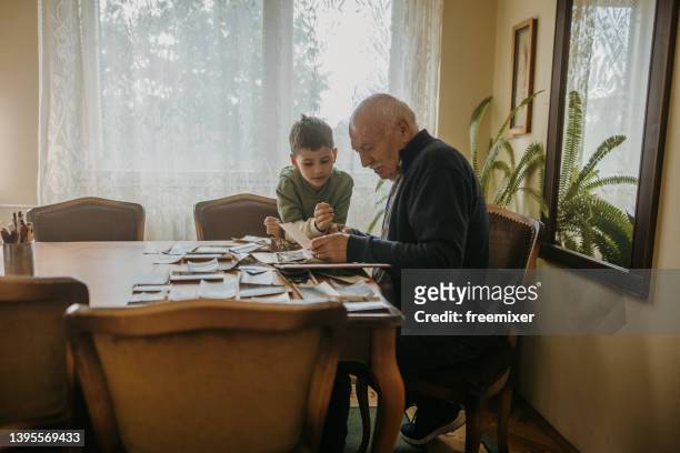 grandfather showing pictures to grandson - multi generation family photos imagens e fotografias de stock