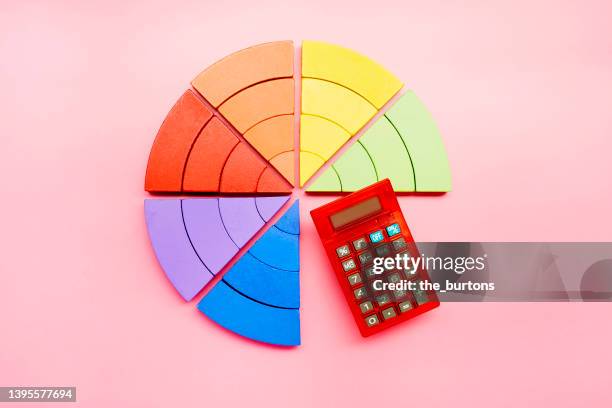 high angle view of a pie chart made of colorful building blocks and red calculator on pink background - dividere foto e immagini stock