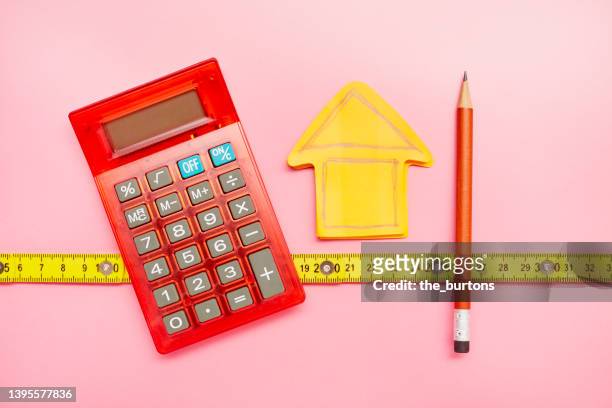 high angle view of calculator, a drawing of a house on an orange notepad and a pencil - house sale stock-fotos und bilder