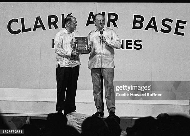 Canadian-born American media personality Art Linkletter is awarded a plaque by an unidentified man during a performance as part of a USO tour at...