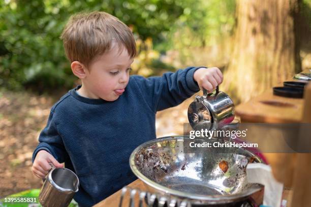 kleiner junge, der draußen mit einer schlammküche spielt - toddler mess stock-fotos und bilder