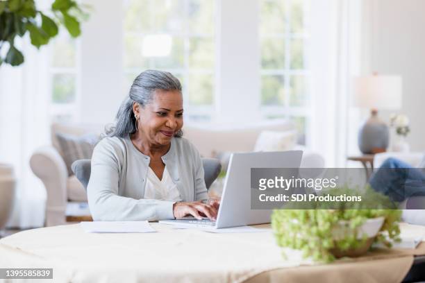 mutter sitzt an ihrem computer und beantwortet e-mails - mature reading computer stock-fotos und bilder