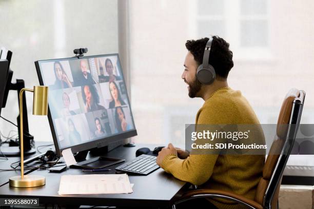 remote employee uses his headphones to attend a video conference - young businessman using a virtual screen stockfoto's en -beelden