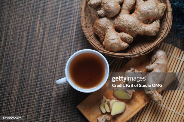 a cup of ginger tea with ginger roots on the table - ginger stock-fotos und bilder