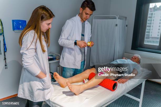 physiotherapist is conducting leg rehabilitation on his old patient - kinesiotape stock pictures, royalty-free photos & images