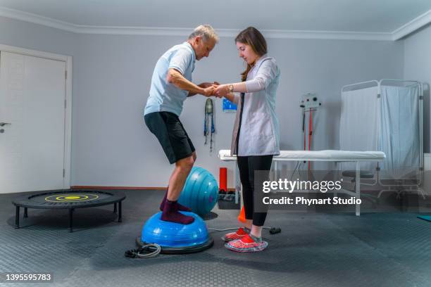 senior man physical rehab patient standing on bosu ball - parkinsons disease stock pictures, royalty-free photos & images