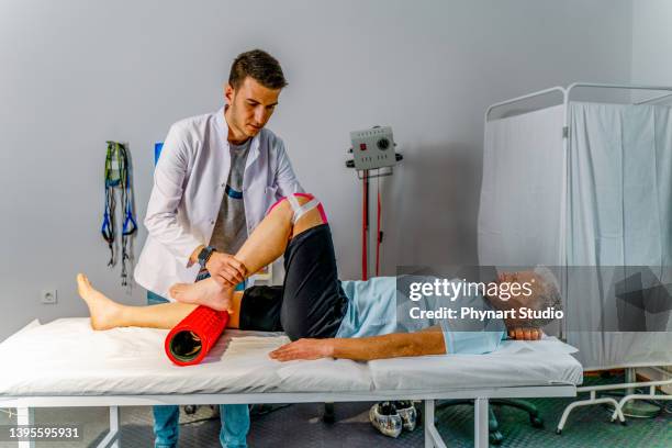 physiotherapist is conducting leg rehabilitation on his old patient - kinesiotape stock pictures, royalty-free photos & images