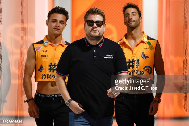 Lando Norris of Great Britain and McLaren and Daniel Ricciardo of Australia and McLaren walk through the Paddock with The Late Late Show host James...